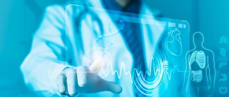 Medical professional in white coat touching digital interface showing heart rhythm and human anatomy in blue tones.