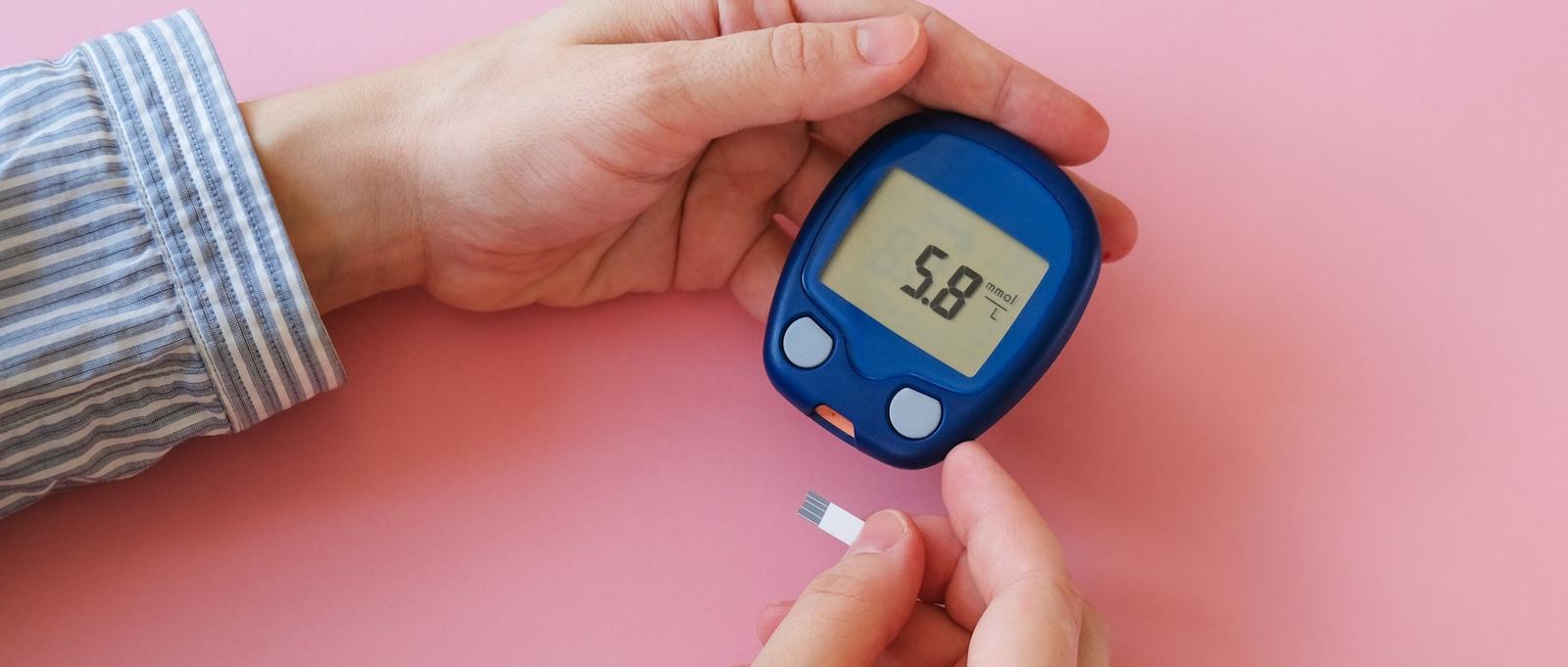 A close up of a pair of hands holding a glucometer.