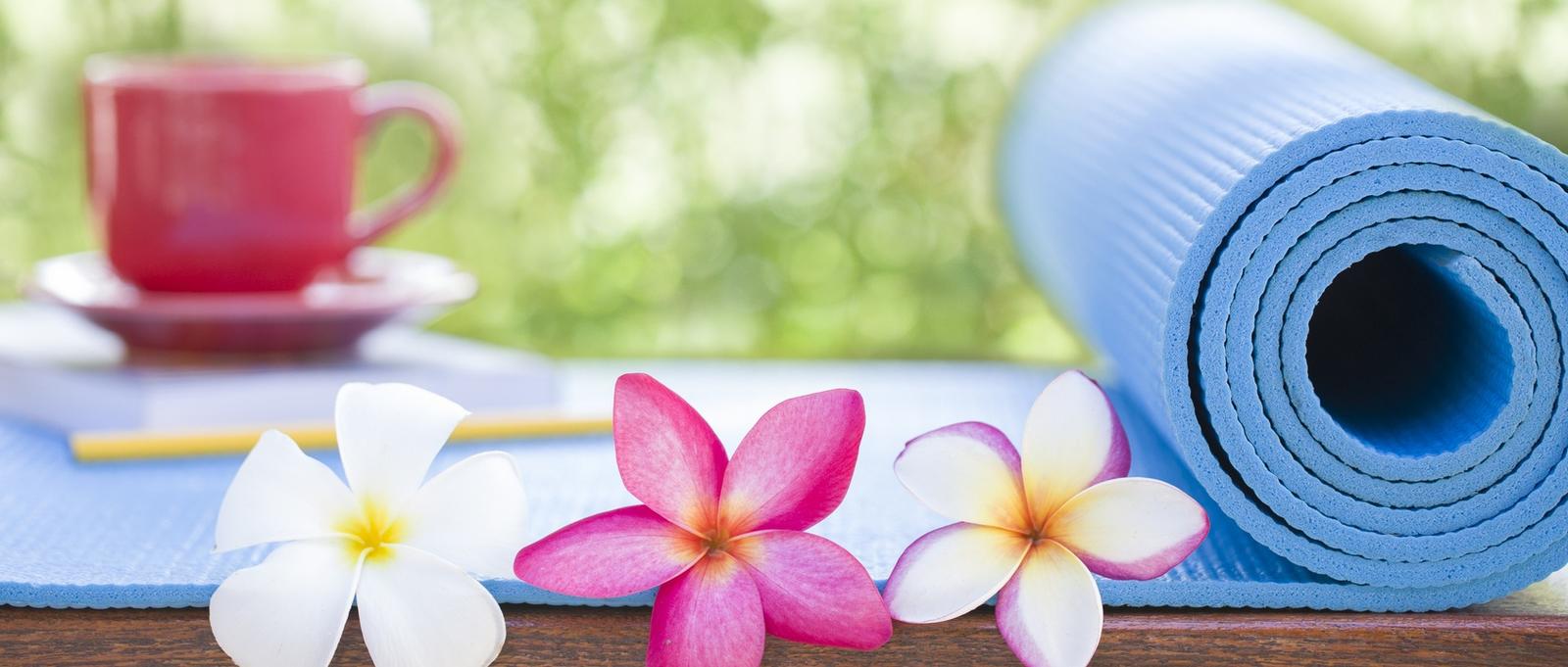 Blue yoga mat, red mug with pink and white flowers