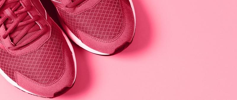 Top view of pinky red trainers against a pink background