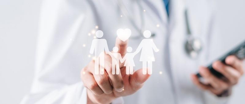 Medical professional in white coat holding a digital family icon while using a smartphone in their other hand.