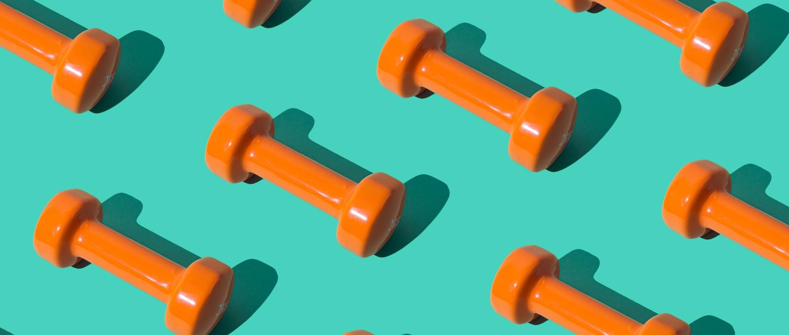 Creative pattern composition made of orange dumbbells on pastel green background. Minimal fitness, healthy lifestyle and sport concept. Trendy exercise and fitness background idea.