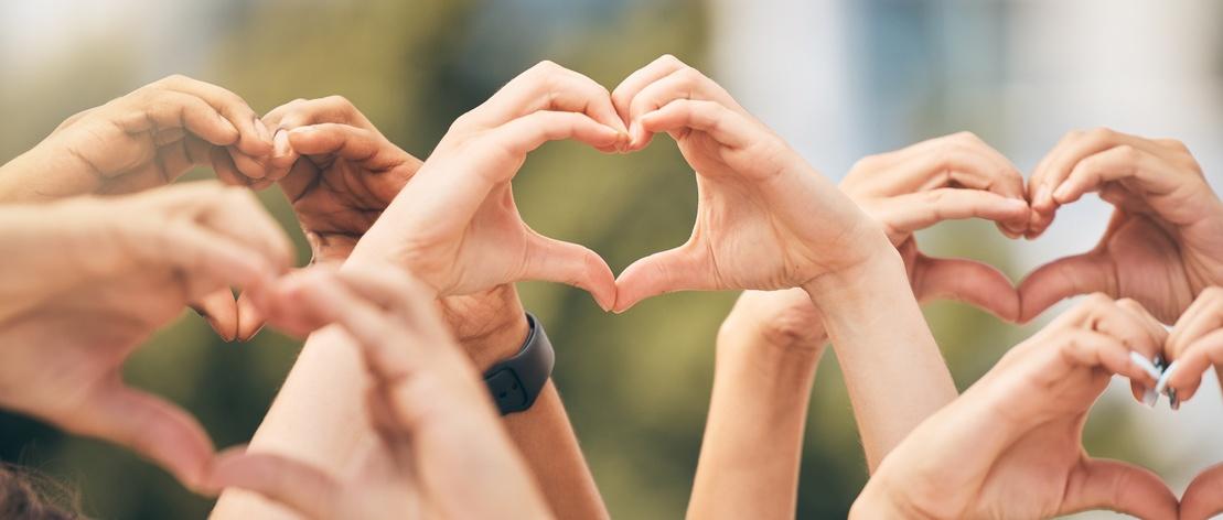 Hand, heart and love with a group of people making a sign with their hands outdoor together in the day. Crowd, freedom and community with man and woman friends doing a gesture to promote health