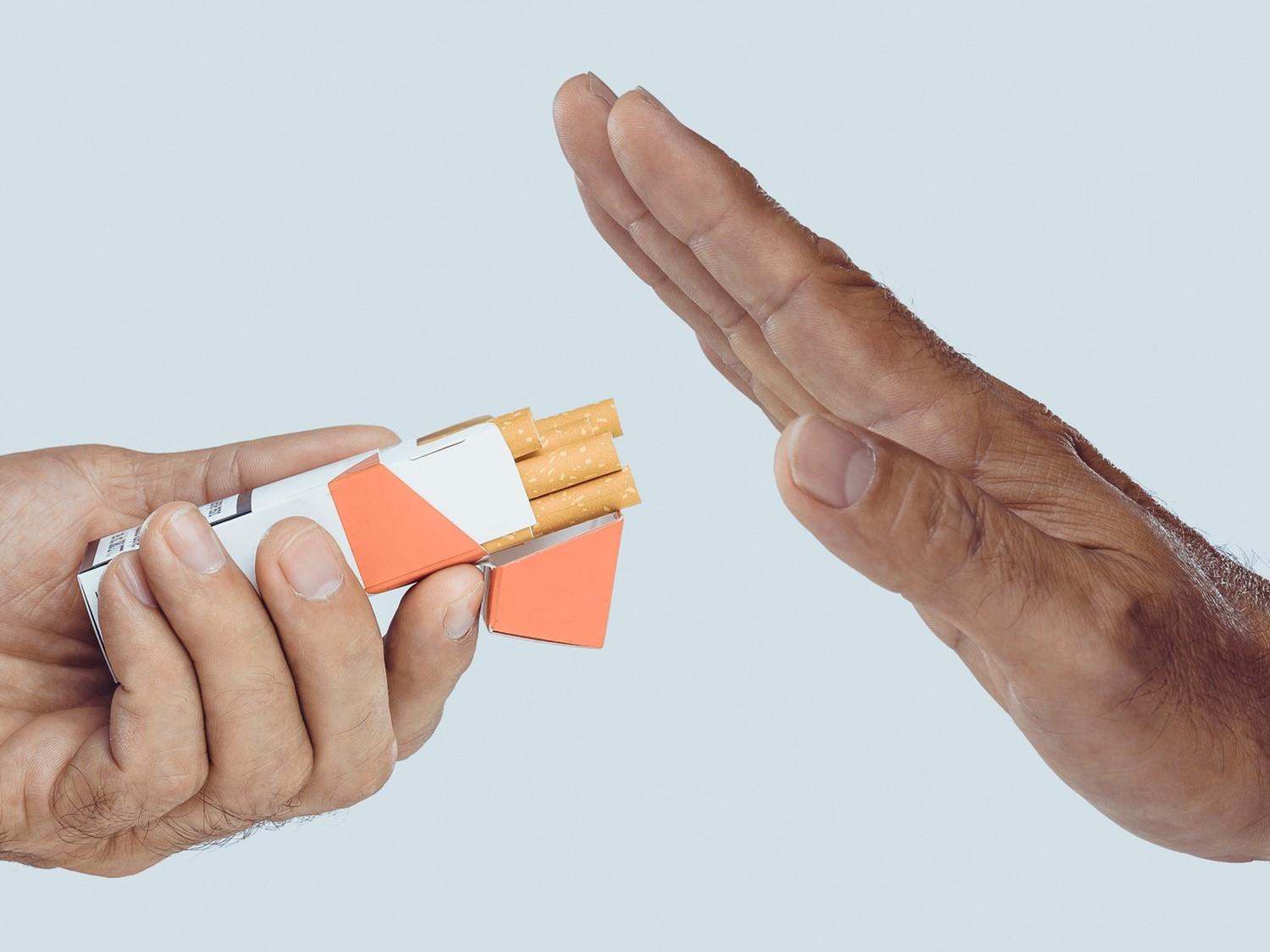 Hand gesturing stop to another hand offering a pack of cigarettes, symbolising quitting smoking or refusal.