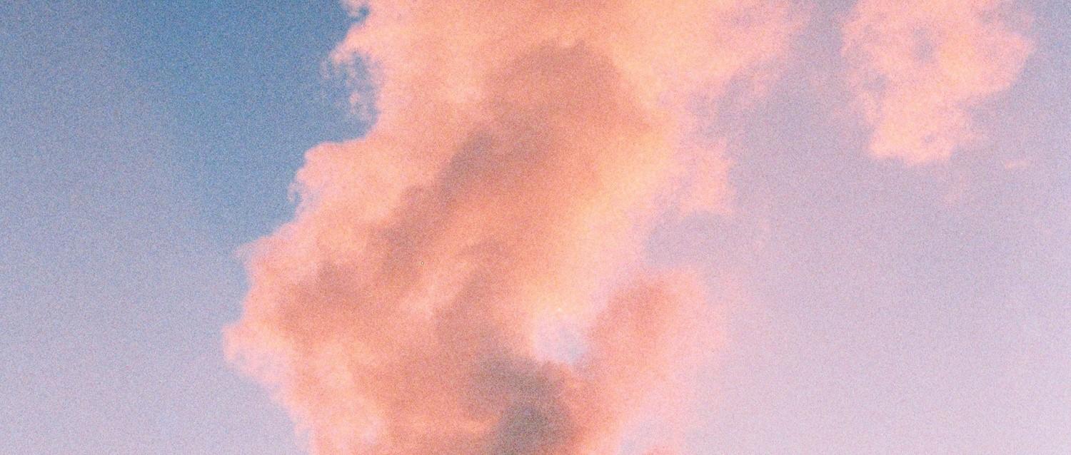 Fluffy pink cloud formation against a blue sky at sunset, creating a dreamy pastel atmosphere.
